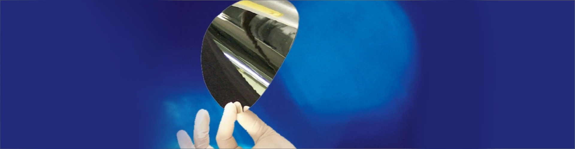 thin stainless steel wafer held by gloved hand